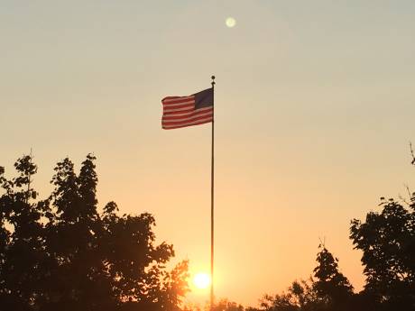 Photo: Sun rising behind flag in Pavilion | The Batavian