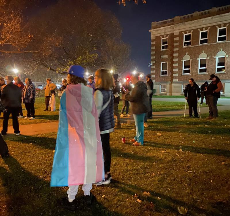 Person draped in flag at vigil