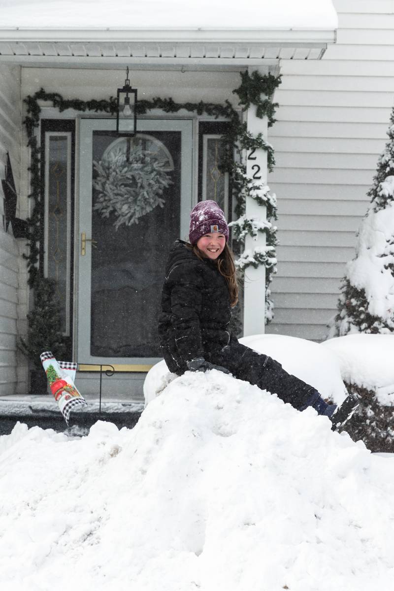 Smiles and fun in the snow by this young girl on her snowbank.  Photo by Steve Ognibene